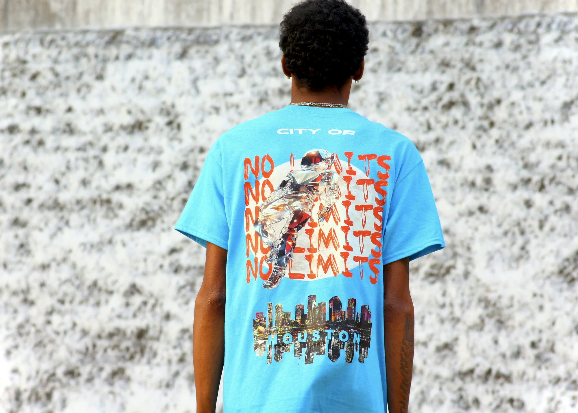Back of the City of No Limits tee against a textured concrete wall